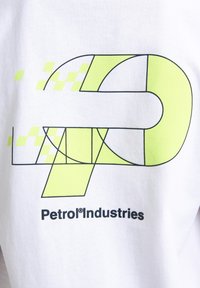 Tricou alb din bumbac, cu un design grafic ce include linii negre și accente galbene strălucitoare, inclusiv un 'P' stilizat și un model de tablă de șah.