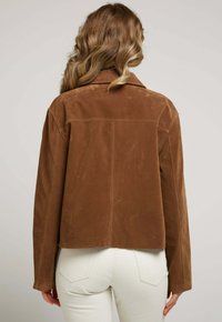Veste en daim marron avec un col classique, des manches longues et une coupe courte, présentant des détails de couture minimaux à l'arrière.