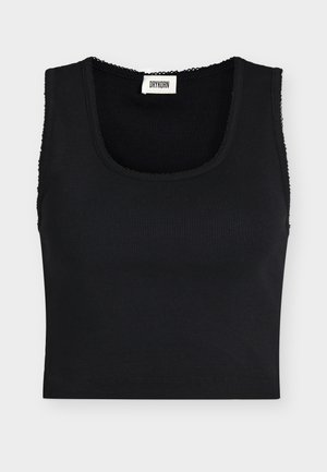 Schwarzes geripptes, kurzes Tanktop mit breiten Trägern und quadratischem Ausschnitt, mit einem kleinen weißen Drykorn Markenlabel innen im Kragen.