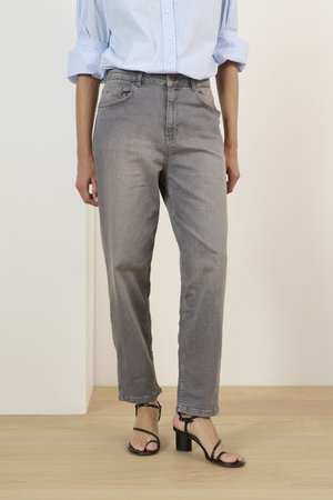 Pelēkas augsto vidukļa džinsus ar brīvu griezumu, kas satur priekšējās kabatas un vieglu izbalēšanu, apvienojot ar melnām siksnu papēžkurpēm.