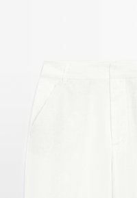 White linen trousers with a smooth texture, featuring side pockets and a tailored waistband. No visible patterns or hardware details.