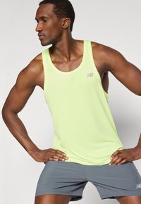 Ανοιχτό πράσινο αμάνικο τοπ με ριμπ υφή, που διαθέτει μικρό γκρι λογότυπο, συνδυασμένο με γκρι σορτς. Το μοντέλο ποζάρει με το ένα χέρι στη μέση.