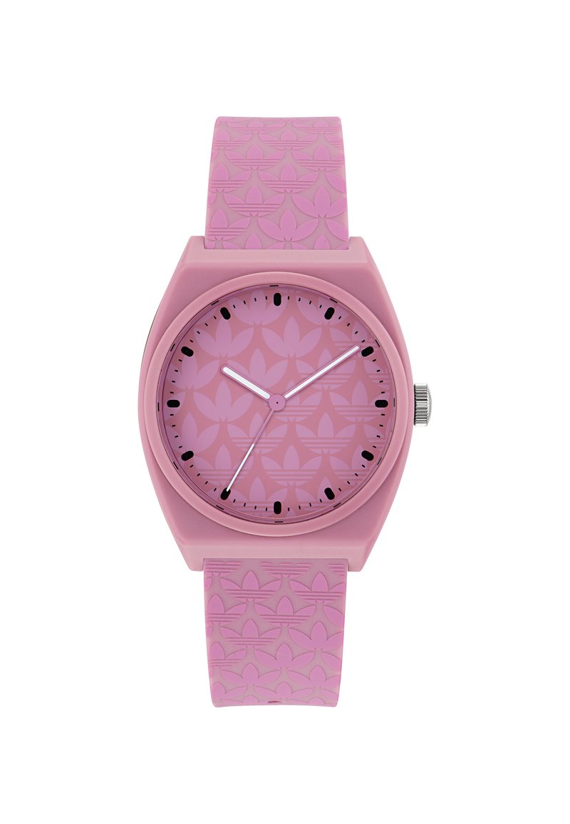 Pink silicone watch with a patterned strap, round case, and matching dial. Black hour markers and hands contrast against a light pink background.