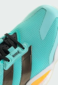 Türkise Sport-Schuh mit einem Obermaterial aus Mesh, schwarzen Schnürsenkeln und glänzenden grauen Akzenten. Enthält strukturierte Details und eine markante Gummisohle.