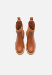 Botas de tobillo impermeables marrones con un cuerpo de cuero suave y parte superior de textil acanalado. Presenta una suela de goma resistente y lengüetas para facilitar ponerlas y quitarlas.