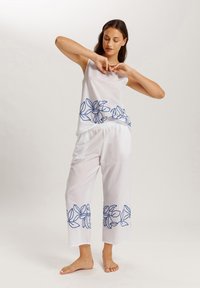 Top sin mangas blanco y pantalones recortados con bordado de hojas azules en el dobladillo. Tela ligera con una textura suave, corte relajado.