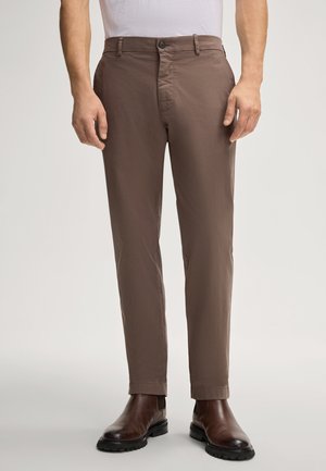 Pantaloni in cotone marrone misto con vestibilità slim, dotati di chiusura a bottone, passanti per la cintura e una texture liscia, abbinati a stivali marroni scuri.
