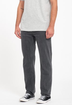 Gray denim jeans with a straight cut, featuring a faded finish and basic five-pocket design, paired with black sneakers.