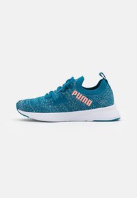 Zapatillas deportivas en color verde azulado con parte superior de punto texturizado, suela blanca y detalles del logo en rosa. Presenta un diseño con cordones y una pestaña trasera.