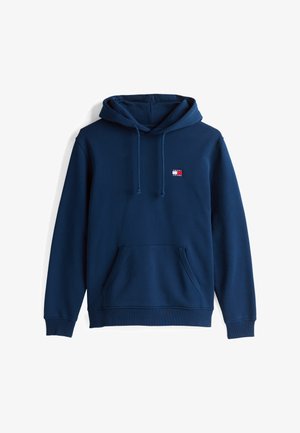 Marineblå hettegenser med kengurulomme, snorjustering i hetten, og en liten logo-lap med røde og hvite detaljer på brystet. Myk tekstur.