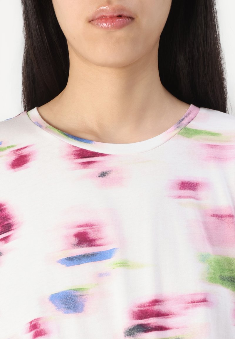 Kurzärmliges weißes Oberteil mit abstrakten rosa, grünen und blauen Mustern. Weicher Stoff mit rundem Halsausschnitt und glatter Textur.