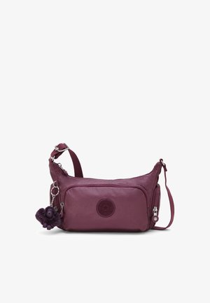 Petit sac bandoulière violet foncé avec sangle réglable, poche zippée à l'avant et un porte-clés singe duveteux attaché.