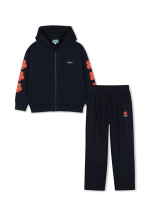 Ensemble sweat à capuche zippé noir et pantalon avec imprimés de fleurs rouges sur les manches et le pantalon, et logo blanc "Kenzo Paris" sur la poitrine et la cuisse.