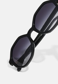 Μα�ύρα οκτάγωνα γυαλιά ηλίου με γκρι φακούς gradient και υφή μαύρης βραχίονας. Διαθέτουν τολμηρό, γεωμετρικό σχέδιο για μια σύγχρονη εμφάνιση.