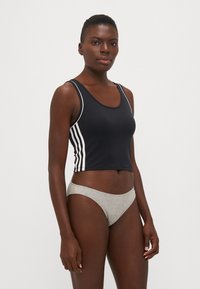 Svart cropped tank topp med hvite side-streker, laget av glatt stoff. Kombinert med lys grå bikini-bunn med middels høyde, myk tekstur.