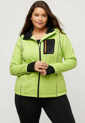 Vihreä fleece-takki, jossa on musta huppu ja vetoketjullinen rintatasku oranssilla yksityiskohdalla. Venytettävää kangasta, jossa on kontrastiväriset ompeluseikat.