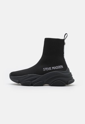 Sneaker noire avec une tige en tricot côtelé et une semelle noire rembourrée. Présente un logo "STEVE MADDEN" blanc sur le côté. Design flexible et élégant.