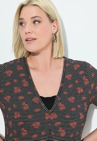 Top a righe bianche e nere con piccoli motivi floreali rossi, design a scollo a V, maniche corte e una sottoveste nera a strati.