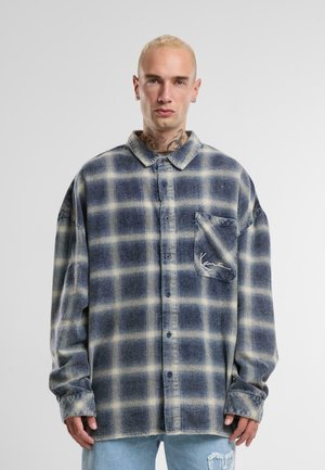 Flannel skjorte med et blåt og beige ternet mønster, med patentknapdesign, lomme detalje og lange ærmer. Blødt, struktureret stof.