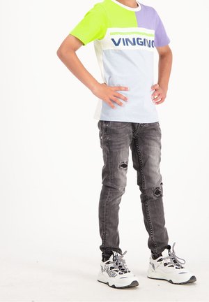 Farbenfrohes T-Shirt mit grünen, hellblauen, lila und weißen Paneelen, mit dem Schriftzug "VINGINO". Getragen mit grauen, ausgefransten Jeans und weißen Sneakern.