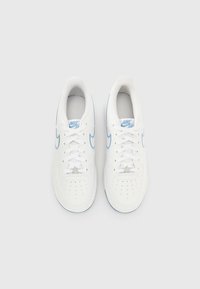 Λευκά αθλητικά παπούτσια Nike Air με ανοιχτό μπλε λεπτομέρειες, διάτρητο σχέδιο, κλείσιμο με κορδόνια και αστέρι στη γλώσσα. Ομαλή υφή δέρματος.