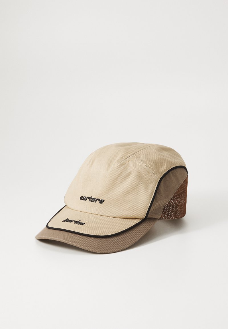 Casquette beige avec des bordures noires, présentant une couronne arrondie et une visière rigide et incurvée. Le panneau arrière a une texture en maille. Des logos sont brodés à l'avant.
