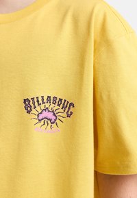 Geel katoenen t-shirt met een grafische print van Australië en gestileerde tekst, aangevuld met contrasterende roze accenten. Ontspannen pasvorm.