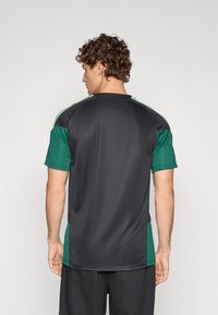 Black and green athletic shirt with short sleeves, featuring contrasting side panels and a smooth, moisture-wicking fabric texture.