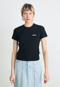 Schwarzes Baumwoll-T-Shirt mit kurzen Ärmeln und rundem Halsausschnitt, mit einem kleinen weißen "Dickies"-Logo auf der linken Brust. Einfaches Design.