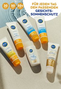 Sechs NIVEA Sun Gesichts-Sonnenschutzmittel in Tuben: weiße und orange Verpackung, mit den Kennzeichnungen SPF 30, 50 und 50+, auf einer hellen Oberfläche angeordnet.