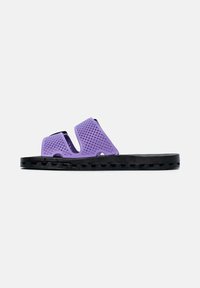 Paarse open-toe sandaal met perforated banden en een dikke zwarte gestructureerde zool, zichtbaar in zijaanzicht op een witte achtergrond.