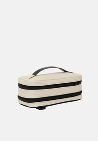 Trousse de maquillage rectangulaire crème avec des fermetures éclair noires, surface texturée et une poignée noire sur le dessus pour un transport facile.