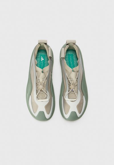 Light beige and green athletic shoes with a textured mesh upper, adjustable elastic laces, and a cushioned turquoise insole.