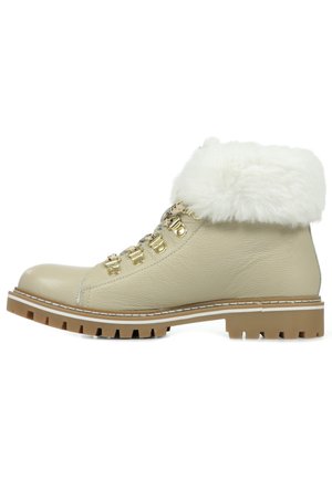 Bottine en cuir beige avec un bord en fausse fourrure blanche, des éléments en métal doré et une semelle robuste. Présente un design à lacets avec une texture matelassée.