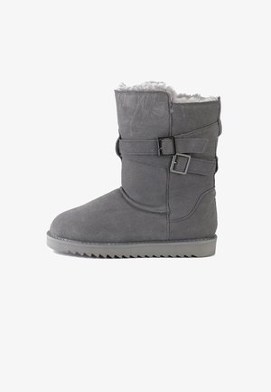 Harmaat mokkasiinit nilkkurit, joissa on keinokuituvuori, kaksinkertaiset solkilangan korostukset ja uurrettu kumipohja. Ominaisuuksiin kuuluu pyöristetty kärki ja keskipituus säärissä.