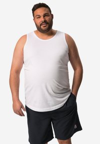 Canotta bianca senza maniche con scollatura rotonda, abbinata a pantaloni corti neri al ginocchio con tasca laterale e logo in evidenza.