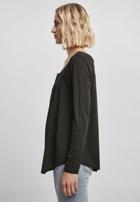 Zwarte langermige top met een ronde halslijn, een ontspannen pasvorm en fijne draping; beschikt over een ronde zoom en een zachte, gladde textuur.
