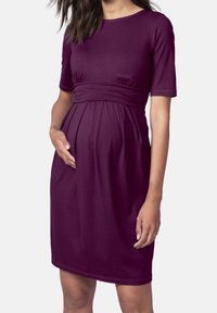 Gravidklänning i djup lila, kortärmad, mjukt tyg, figursydd under bysten med samling, knälength och slät textur.