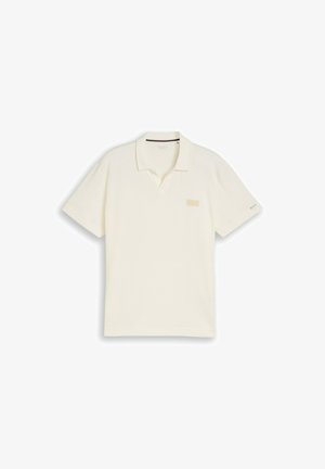 Cremefarbener Poloshirt mit kurzen Ärmeln, Kragen, kleinem Brustaufnäher und dezentem Logo am linken Ärmel.