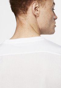 Witte sportieve shirt met een ademende mesh achterzijde, ronde hals en korte mouwen, met een gladdige textuur en strakke lijnen.