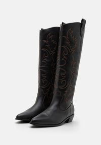 Mustad musta nahast cowboy saapad terava nina, keeruka pruuni tikandiga ja dekoratiivsete mustritega säärtes; madalad plokknõelad.