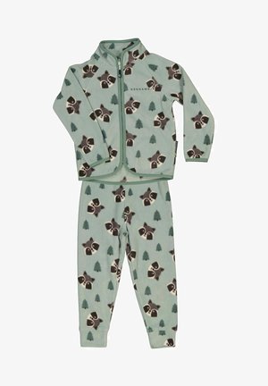 Kind, das einen hellblauen Fleece-Anzug mit Waschbär- und Baummustern trägt, kombiniert mit leuchtend blauen Wanderschuhen mit orangenen Schnürsenkeln.
