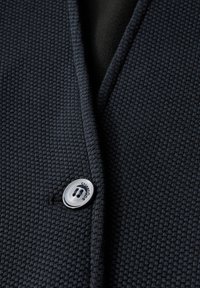 Marinblå strukturstickad cardigan med ett vävt mönster, som har en rund silverknapp med graverad text och ett slätt inre foder.