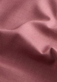 Miękka, pomarszczona tkanina o delikatnej, tkanej fakturze w stonowanym kolorze mauve, ukazująca łagodne fałdy i subtelne cienie.