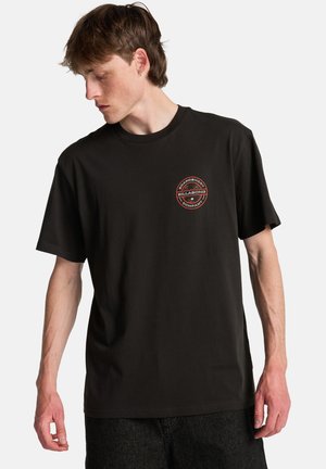 Czarna bawełniana koszulka z okrągłym nadrukiem w kolorze czerwonym i białym na lewej piersi. Krótkie rękawy, okrągły dekolt, luźny krój.