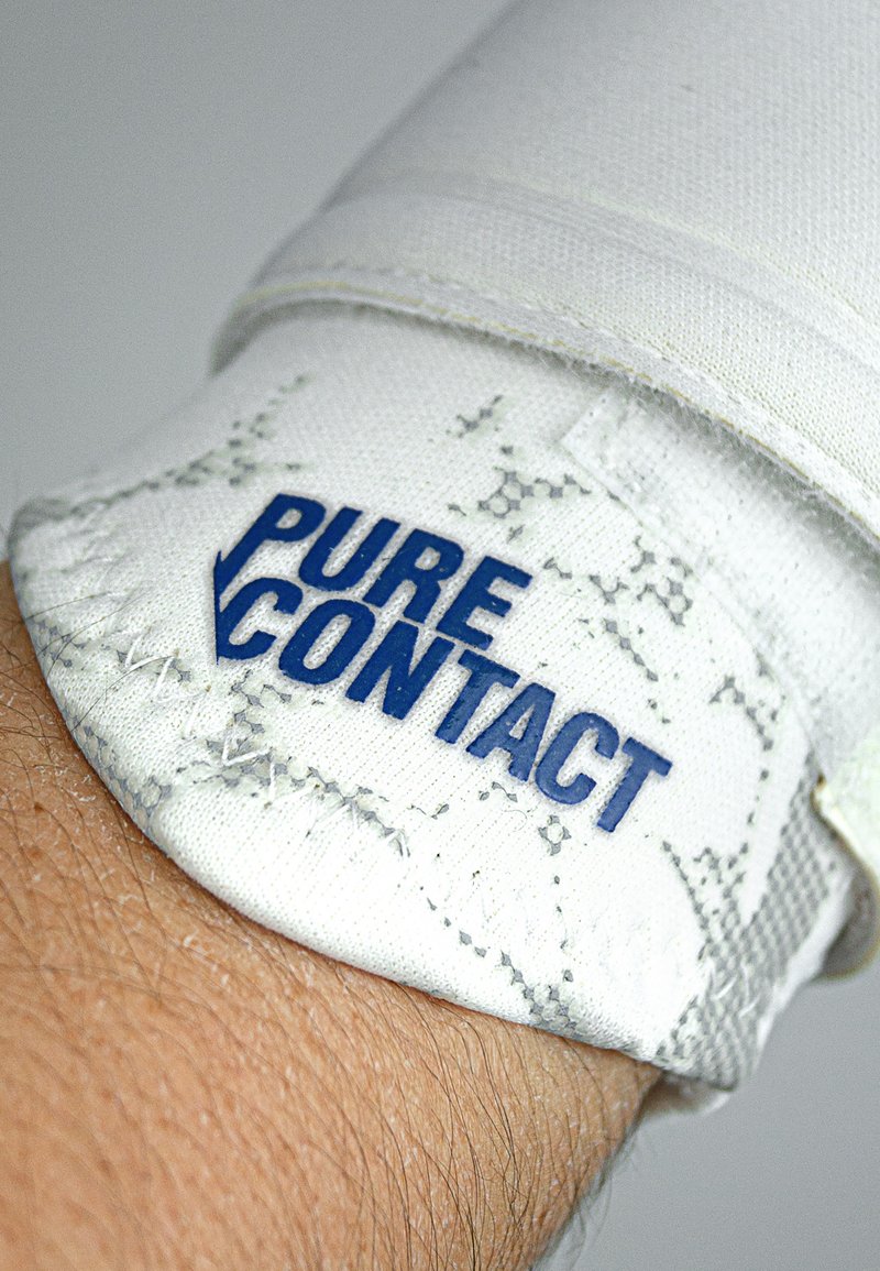 Braccialetto in tessuto bianco texturizzato con logo blu "PURE CONTACT". Dettagli di cucitura visibili e un aspetto complessivo aderente attorno al polso.