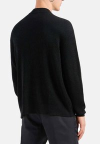 Maglione a coste nero con una vestibilità rilassata, caratterizzato da un collo rotondo e maniche lunghe. La vista dal retro mostra un tessuto testurizzato e cuciture minime.
