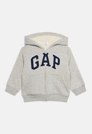 Jasnoszara bluza dla malucha z kapturem, z zamkiem z przodu, podszewką sherpa, kieszeniami kangurzymi i ciemnoniebieskim logo GAP na piersi.