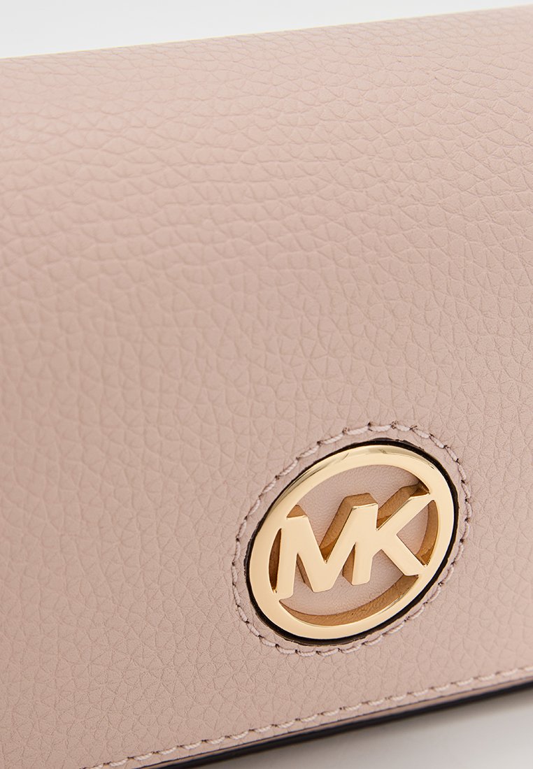 Portefeuille en cuir texturé rose clair avec un logo circulaire en ton doré embossé au centre. Surface douce et bords cousus contrastants.