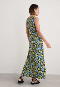 Rochie maxi florală cu un model de flori albastre și galbene pe un fundal negru, design fără mâneci și siluetă fluidă.